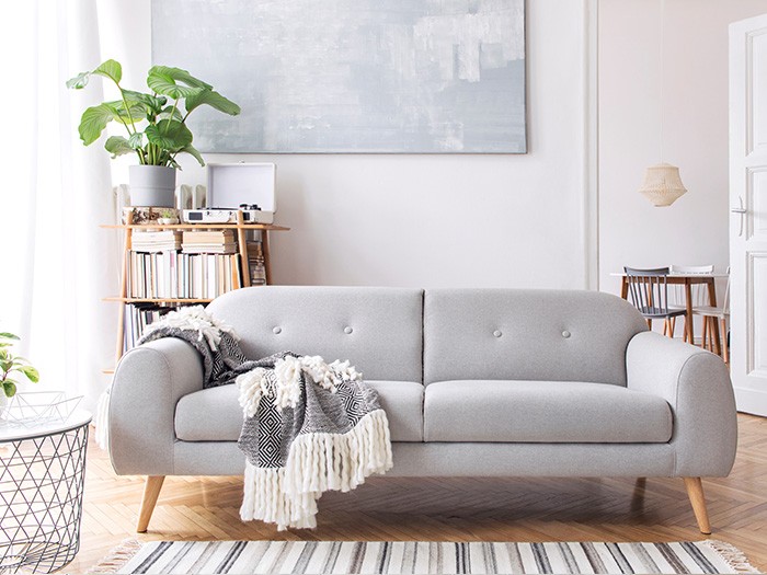 Small living room featuring a small grey sofa with visible legs and a throw blanket draped over the arm and seat.